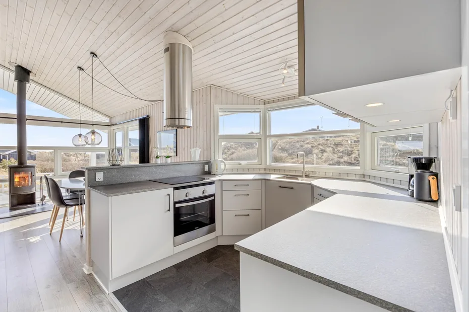 Una cocina abierta y luminosa con una isla central y grandes ventanas.