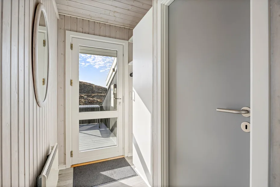 Una entrada luminosa con una puerta de vidrio que da a una terraza.