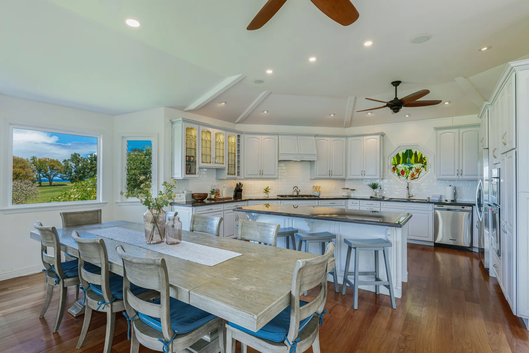 Una cocina y comedor luminosos con gabinetes blancos y una isla grande.