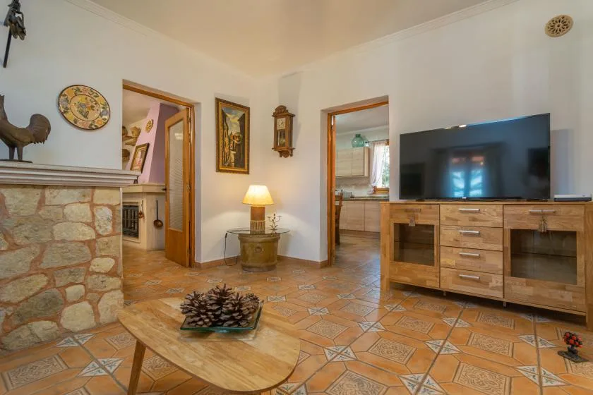A living room with a television on a wooden cabinet and a stone fireplace.