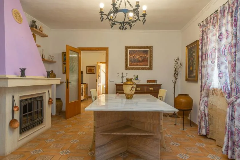 A dining room with a long table, fireplace, and patterned curtains.