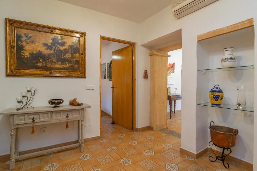 An interior hallway with a wooden doorway, a console table, and built-in display shelves.