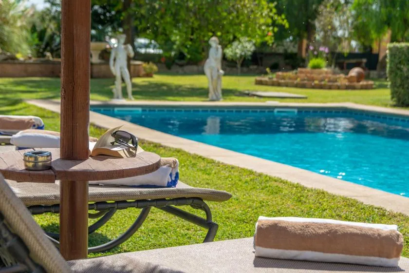 An outdoor swimming pool beside grassy grounds and cushioned lounge seating.