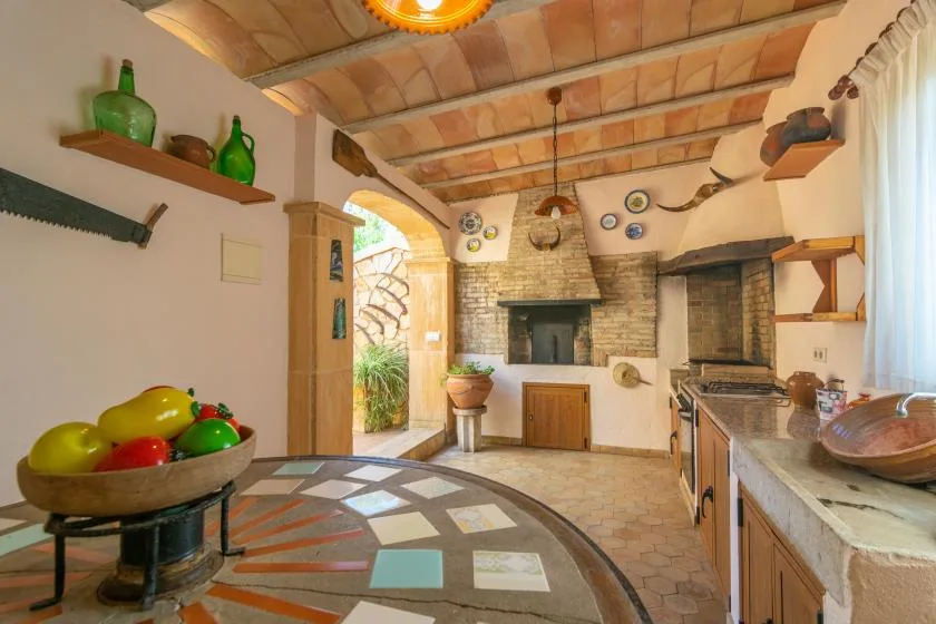 A rustic kitchen with a brick fireplace and colorful tiled floor.