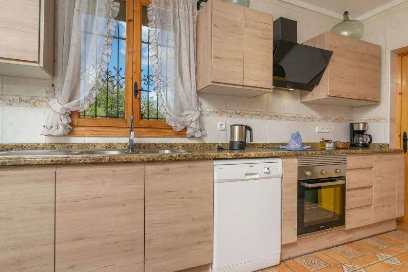 A kitchen with light wood cabinets, a window, and countertop appliances.