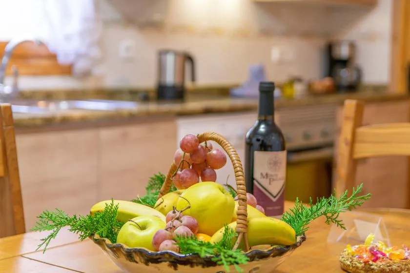 A fruit basket and wine bottle sit on a counter in a kitchen.