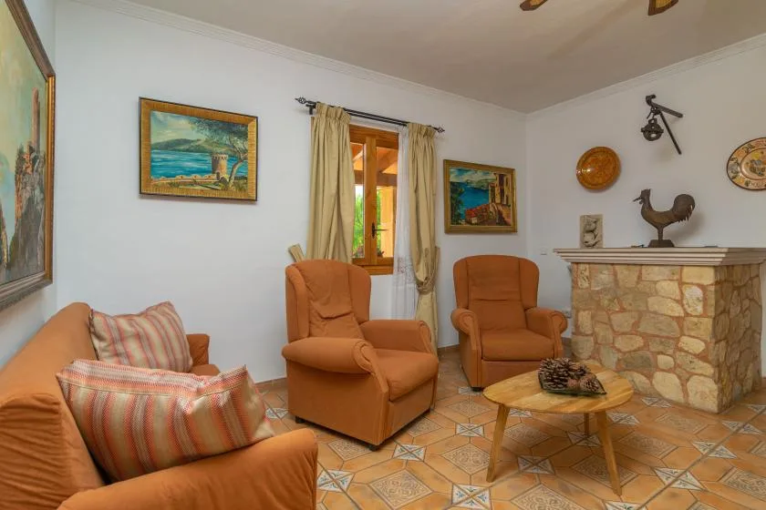 A living room with cushioned seating, a stone fireplace, and a small wooden table.
