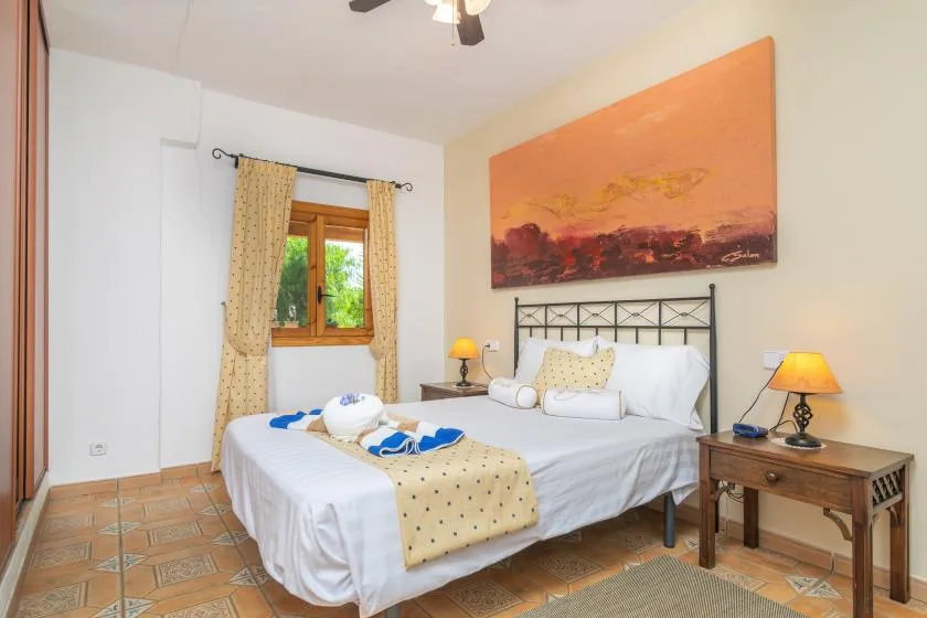 A bedroom with a neatly made bed and a window with curtains.