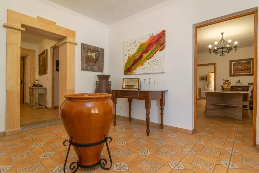 A tiled interior room with a large ceramic vessel and a wooden table.