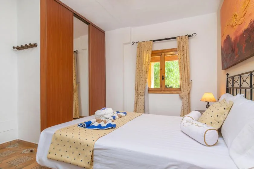 A bedroom with a neatly made bed, patterned curtains, and a window.