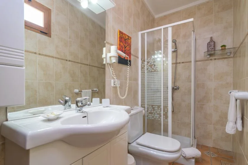 A tiled bathroom with a sink, toilet, and glass shower enclosure.