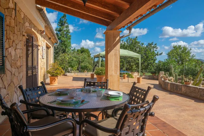 An outdoor dining patio with a table and seating beneath a wooden pergola.
