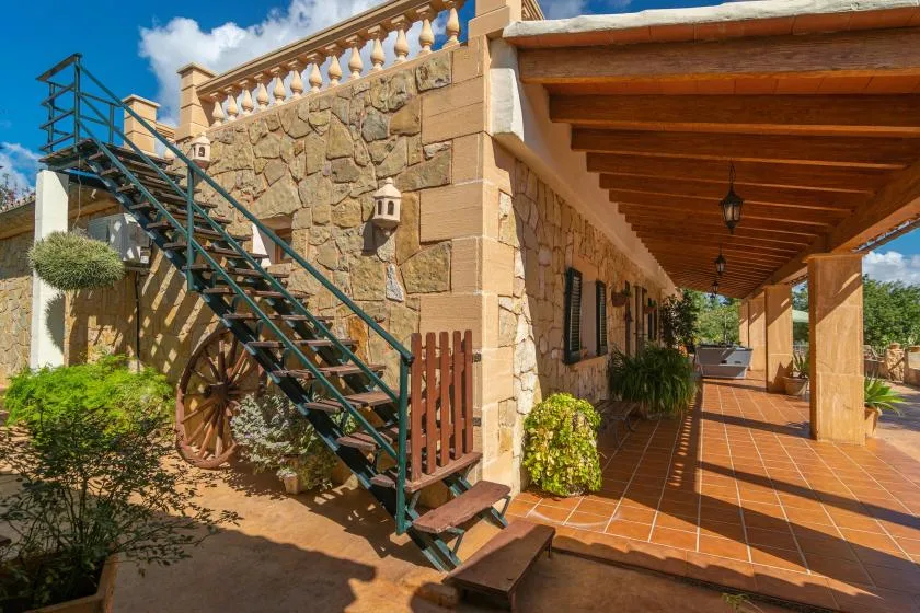 A stone building exterior with an outdoor staircase and a covered tiled patio.