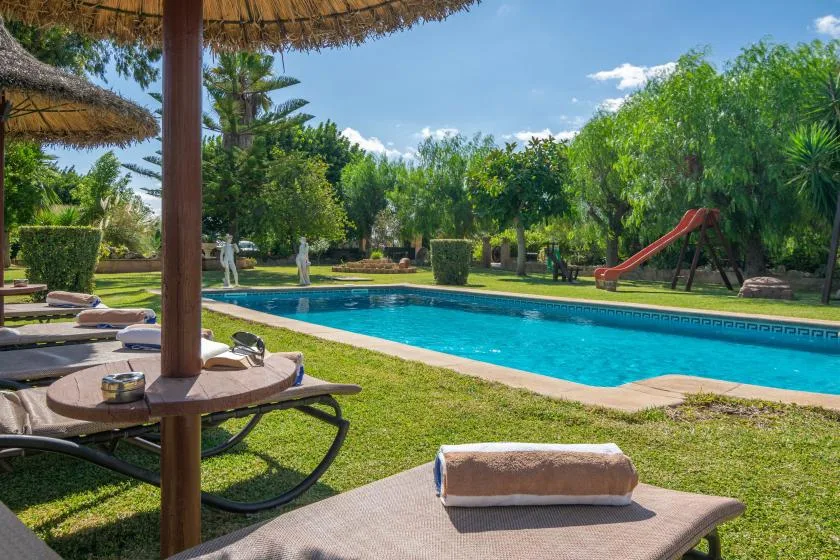 An outdoor pool area with lounge seating and a red playground slide.