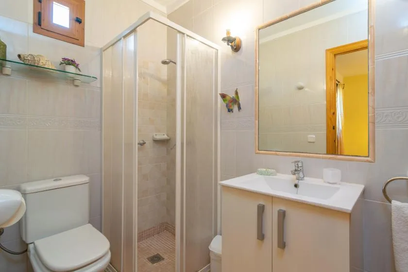A tiled bathroom with a shower, sink, and mirror.