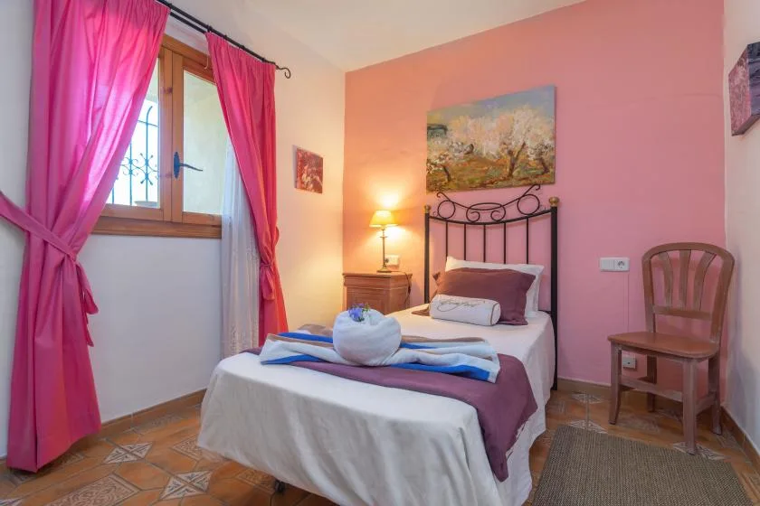 A bedroom with a bed, pink walls, and a curtained window.
