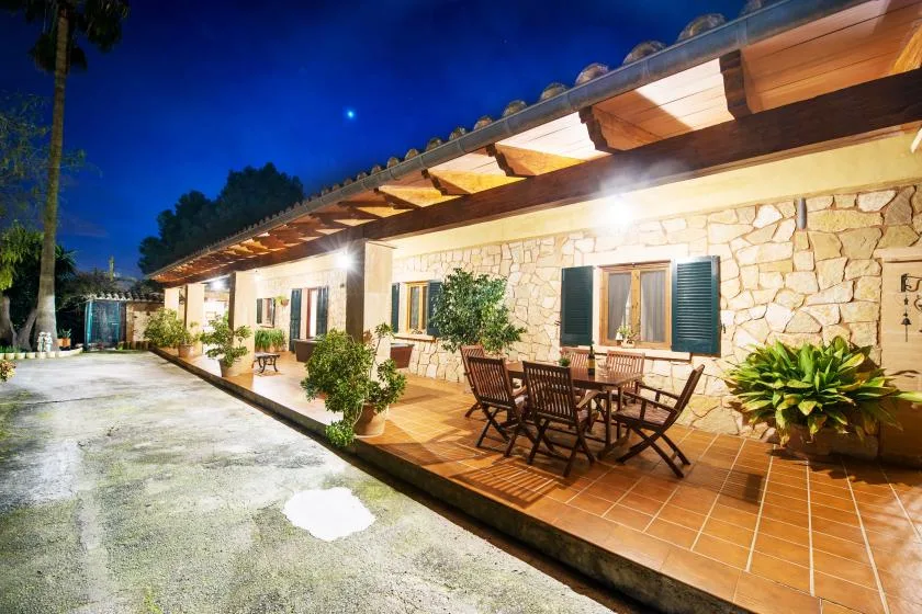 A stone-faced building has a covered patio with outdoor seating at night.