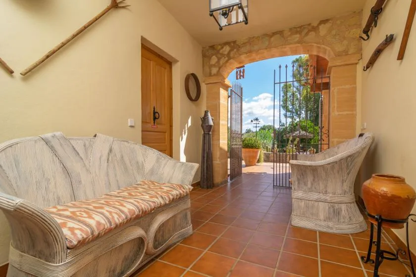 A tiled sitting area opens through an arched doorway to a garden.