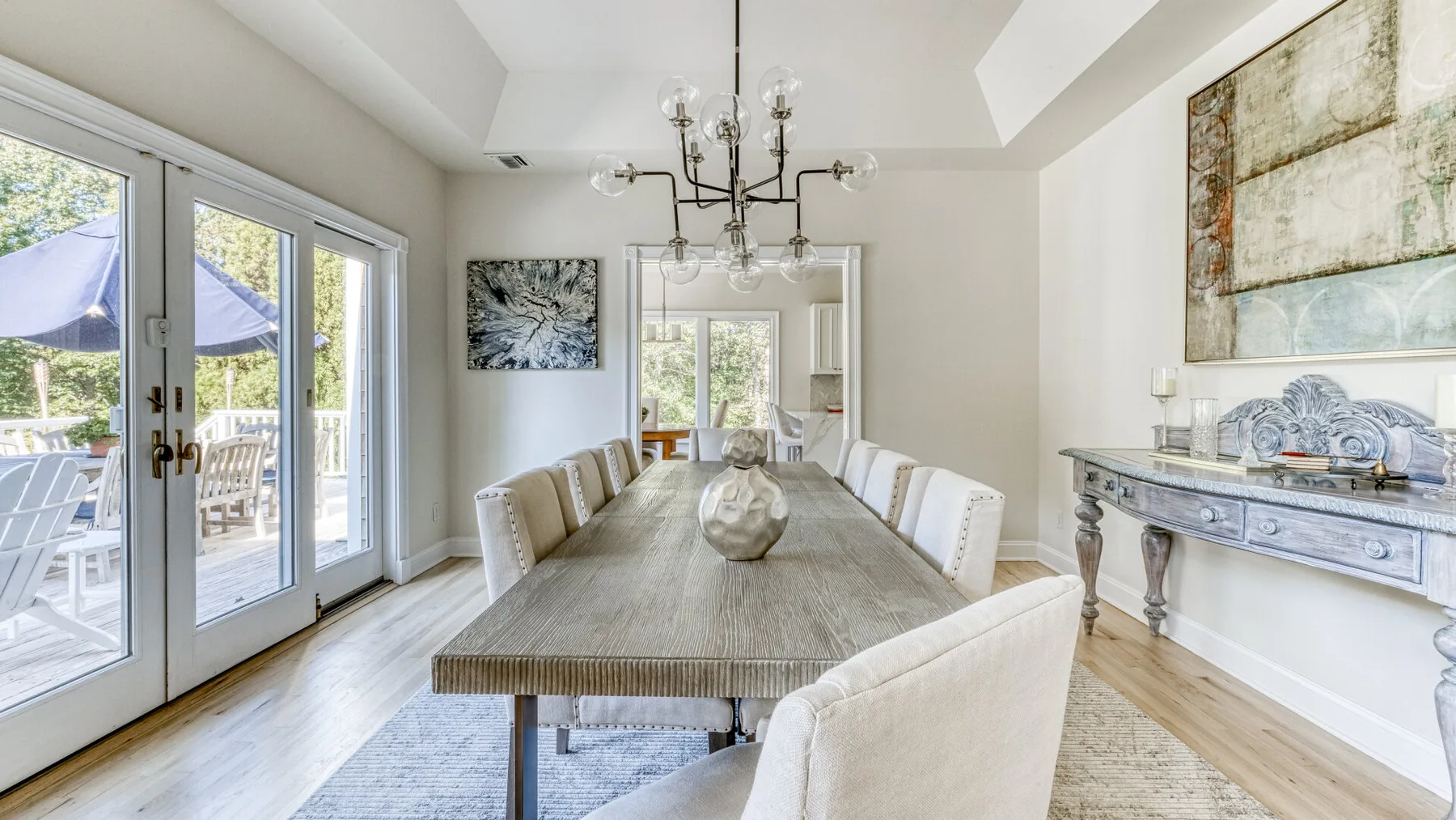 Un comedor luminoso con una mesa larga y sillas junto a grandes ventanas.