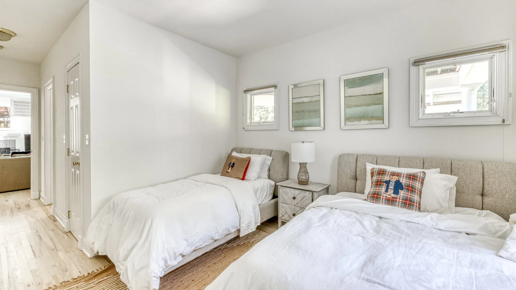 Un dormitorio luminoso con dos camas y cuadros en la pared.