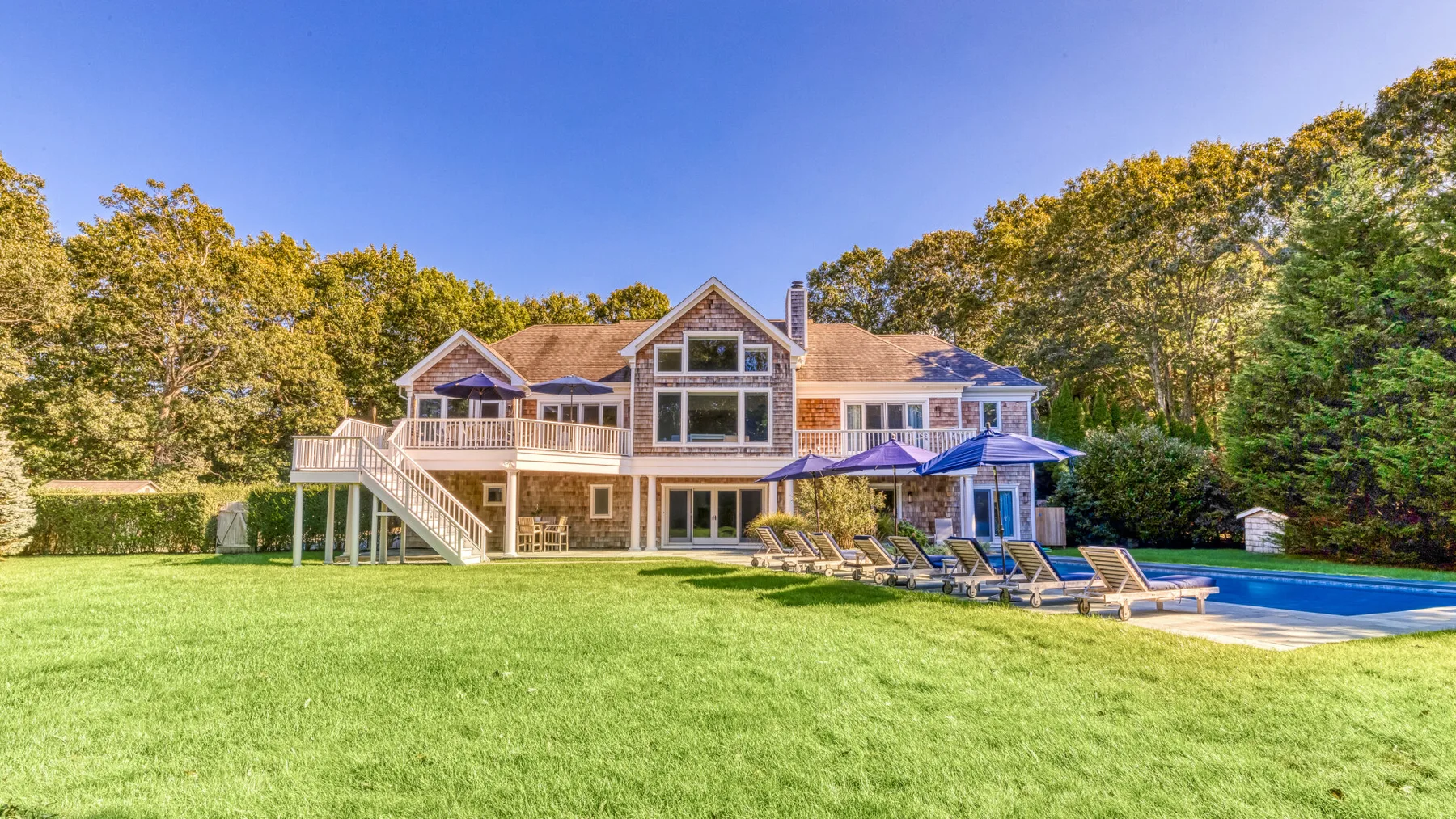 A large house stands beyond a broad lawn, with a swimming pool beside it.