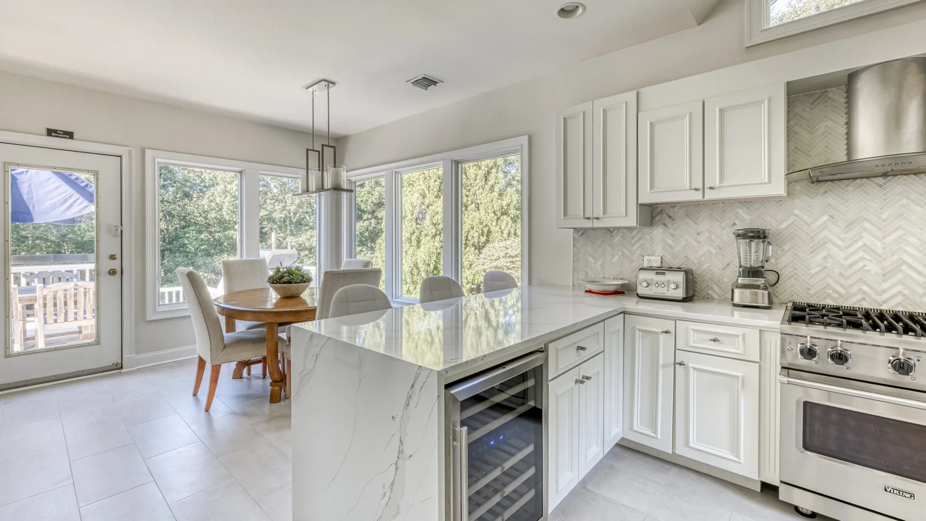 Una cocina luminosa con una isla grande y comedor junto a amplias ventanas.