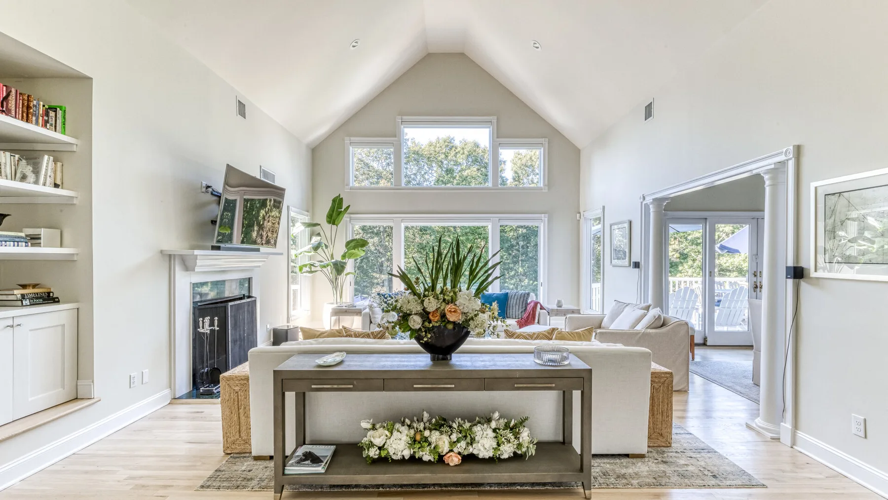 Una sala luminosa con ventanas altas, asientos y un arreglo floral.