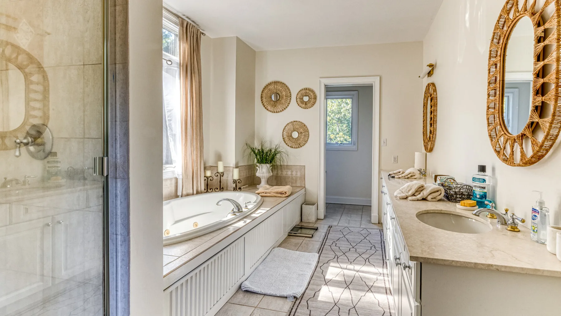Un baño luminoso cuenta con una bañera empotrada, un lavabo y una ventana.