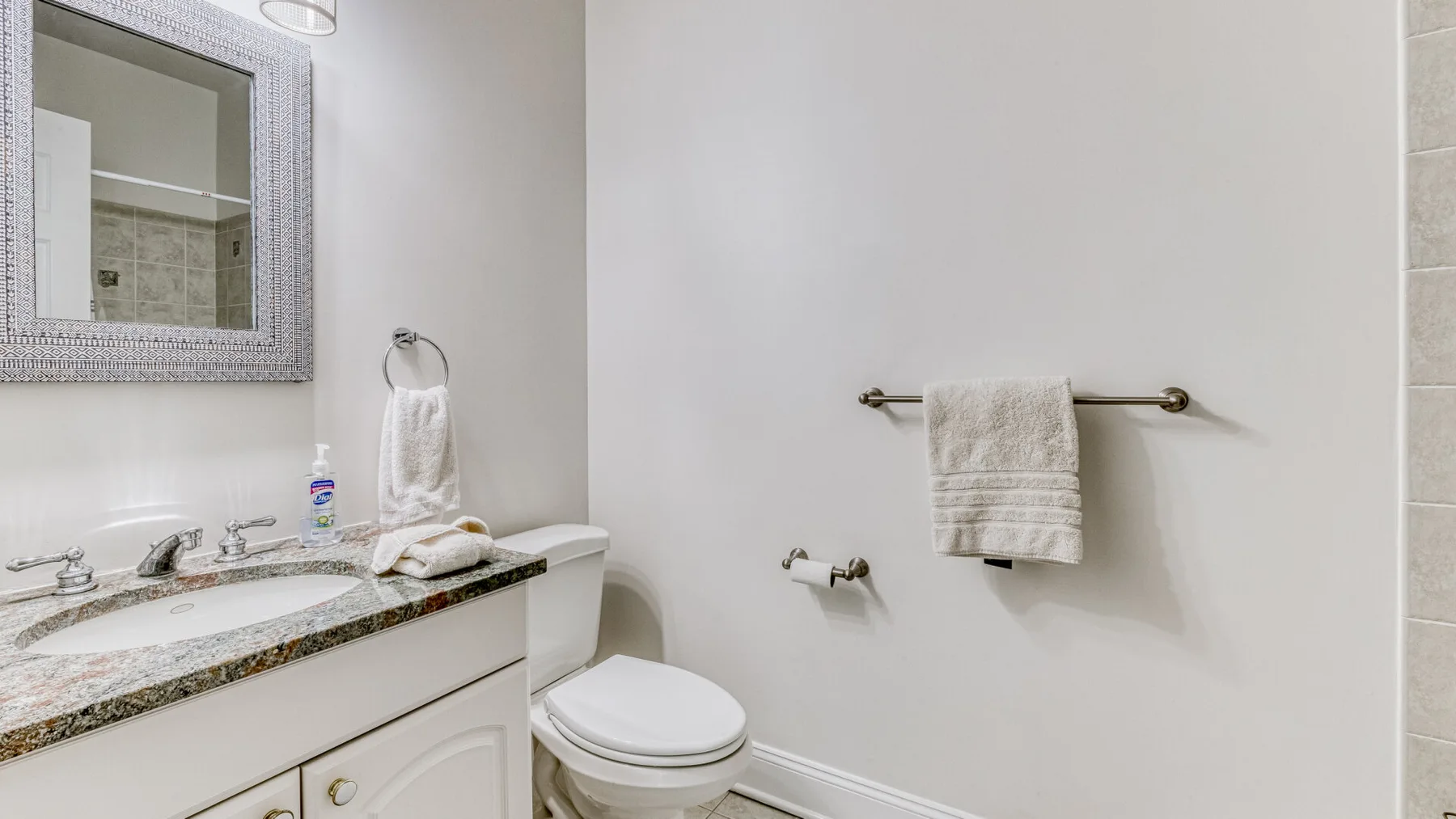 Un lavabo y un inodoro están junto a una toalla colgada en la pared.