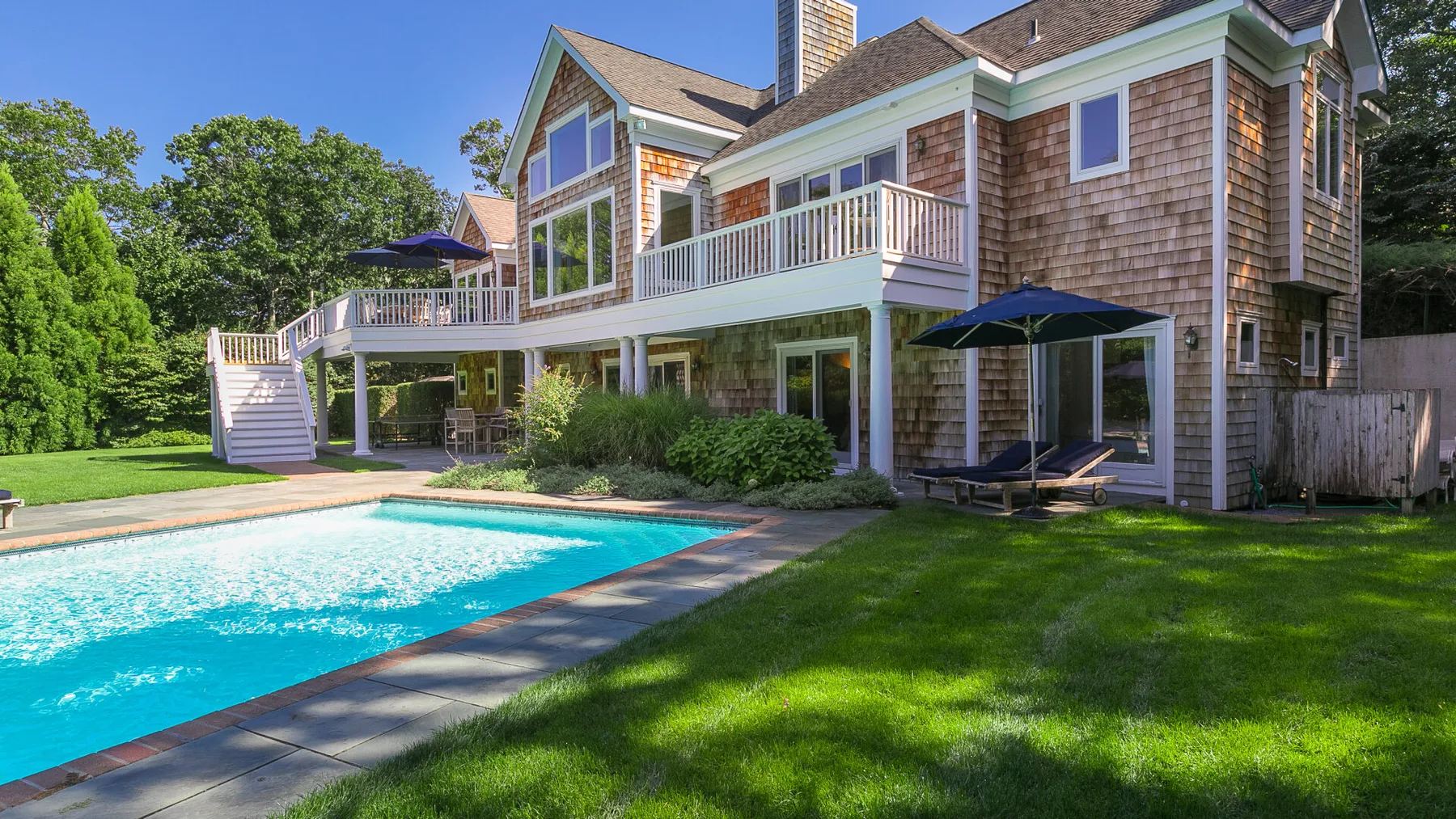 Una casa grande da a una piscina y un césped.