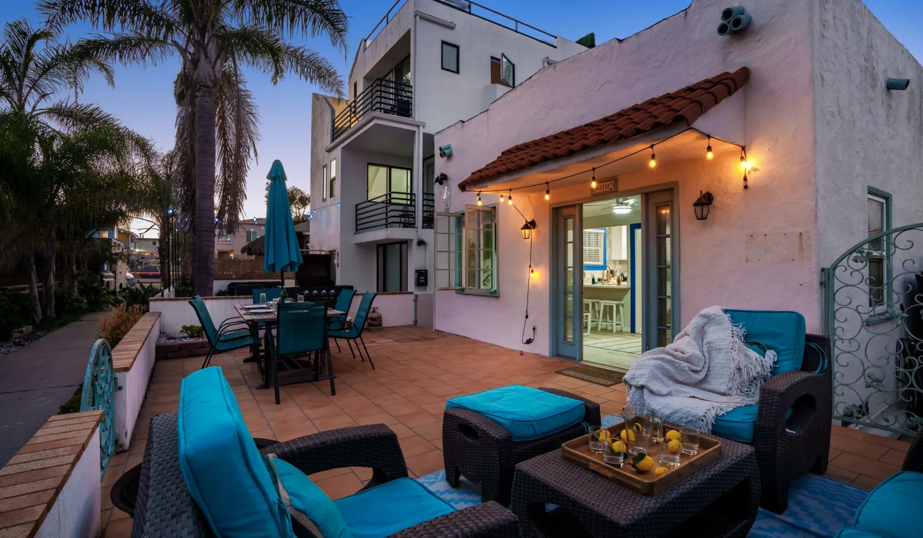 A furnished outdoor patio with seating beside a pink building.