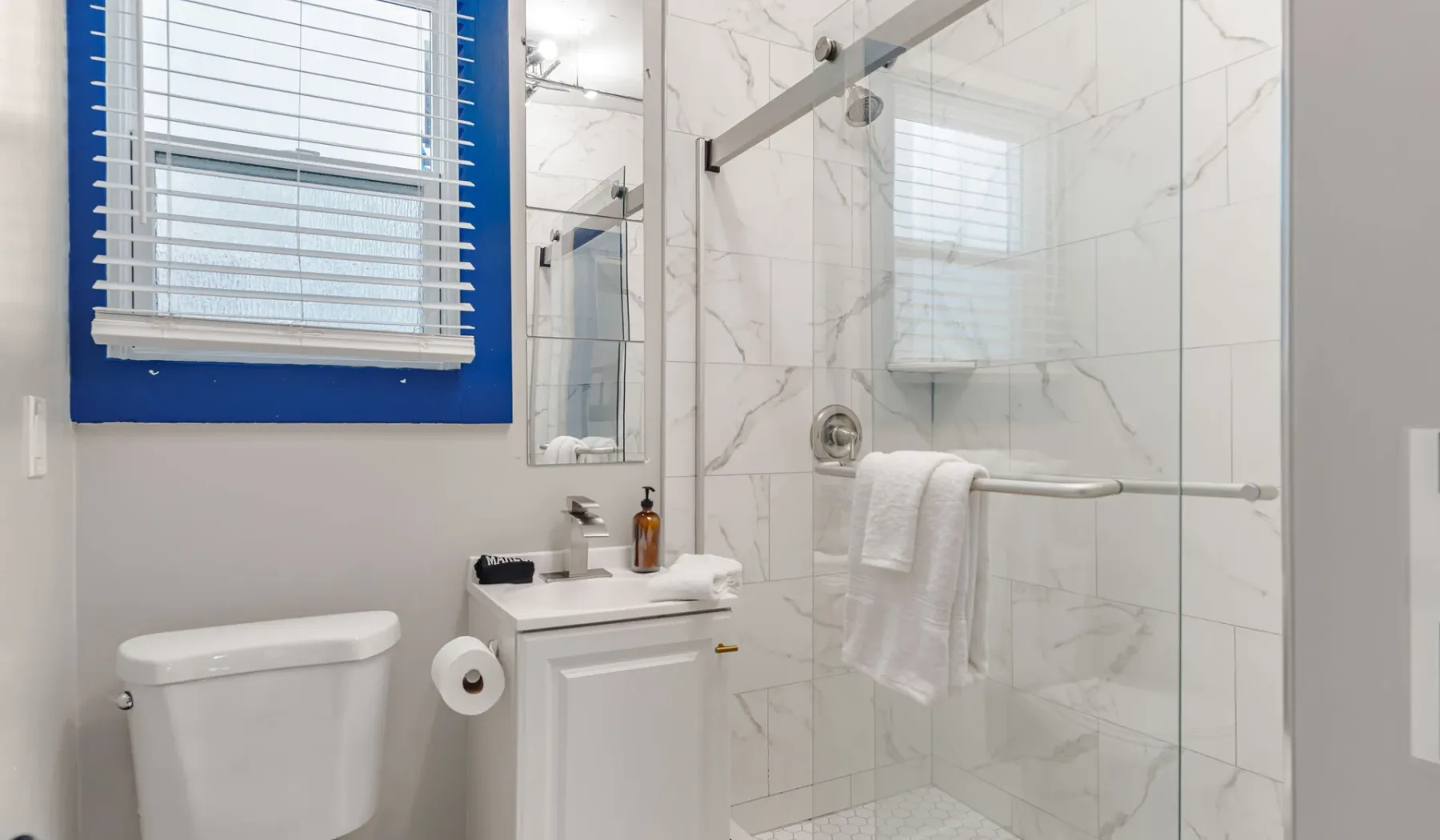 A bright bathroom with a sink, toilet, and glass shower.