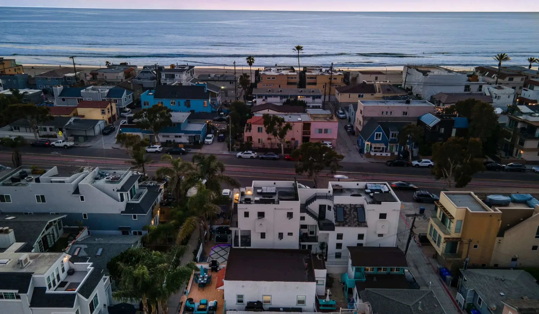 Vista aérea de un barrio costero, con el océano más allá de las viviendas.