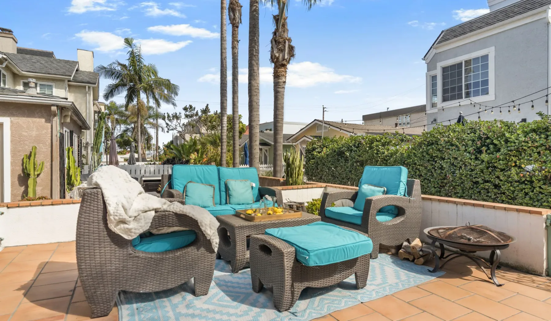 An outdoor patio seating area with turquoise cushions and a small fire pit.