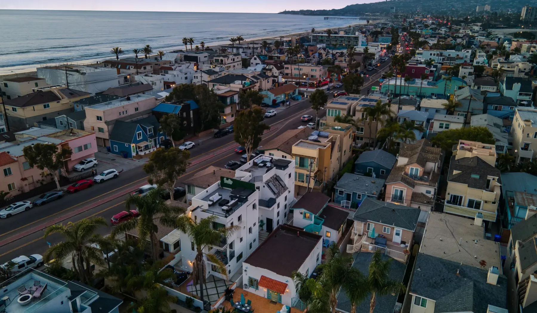 An aerial view of a coastal neighborhood with homes, streets, and the ocean.