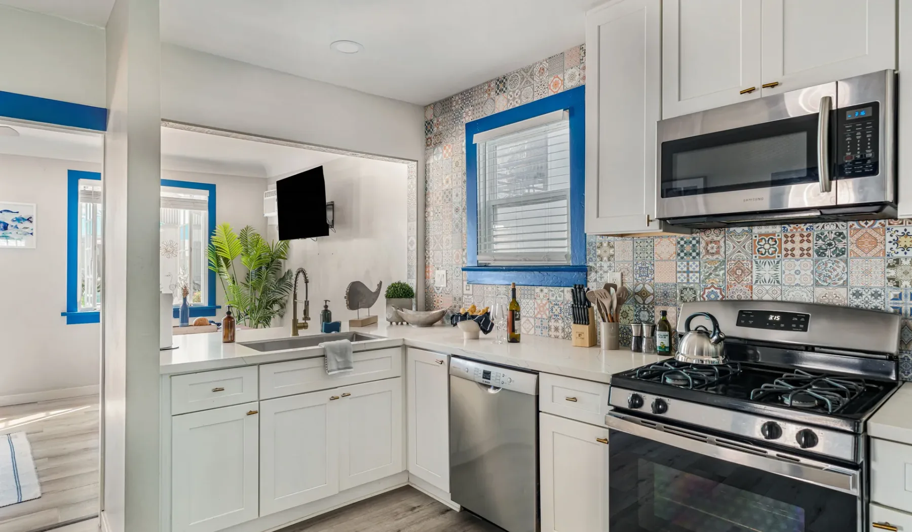 A bright kitchen with white cabinets, patterned backsplash, and stainless steel appliances.