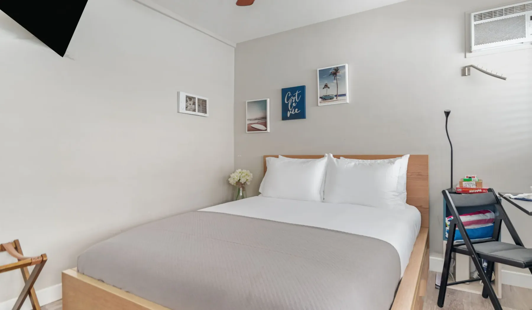 A bedroom with a neatly made bed and framed pictures on the wall.