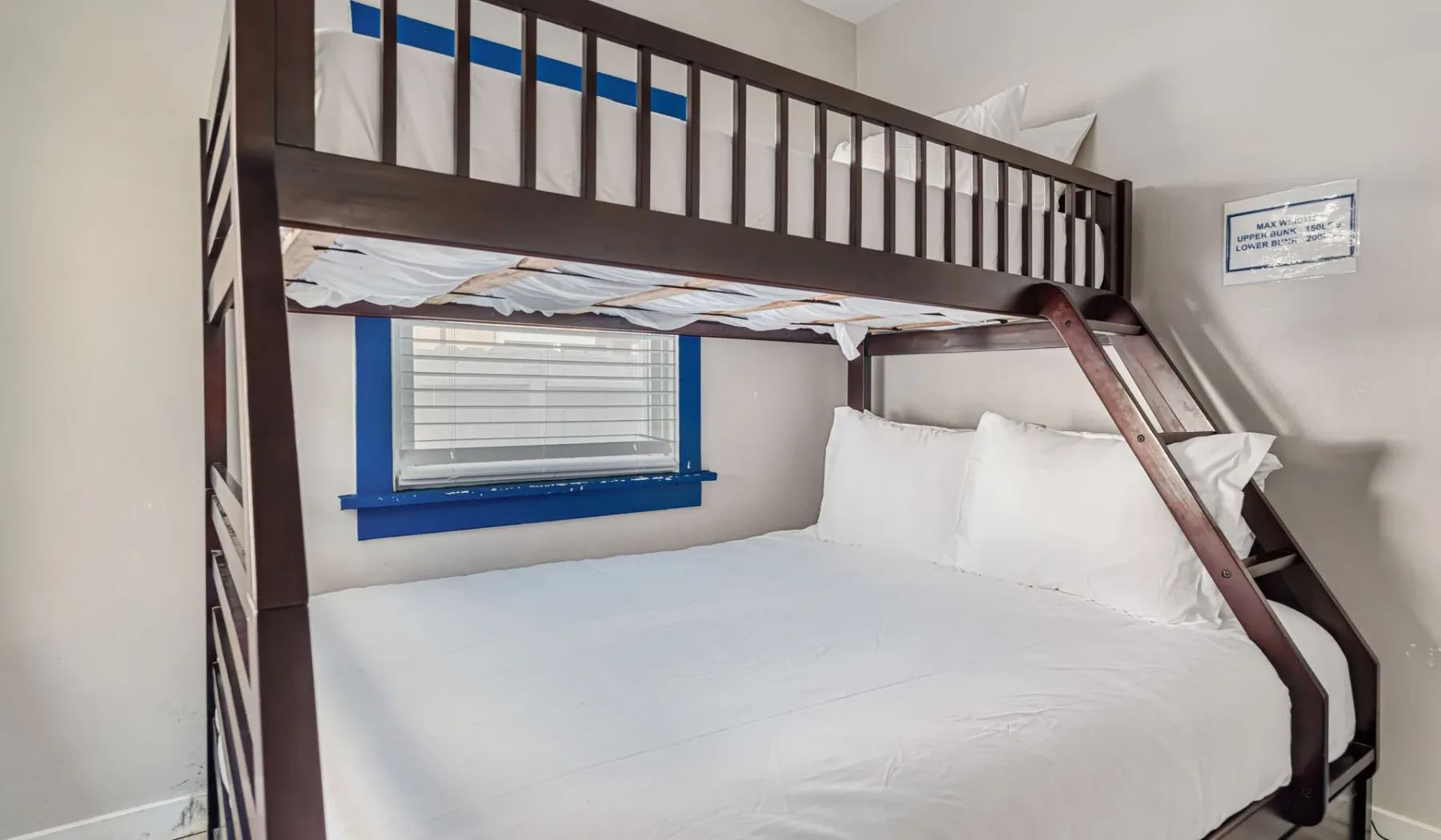 A bedroom with a dark wooden bunk bed and white bedding.
