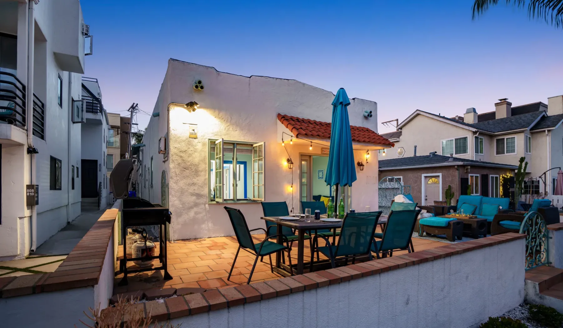 An outdoor patio with dining seating, a table, and a closed umbrella.