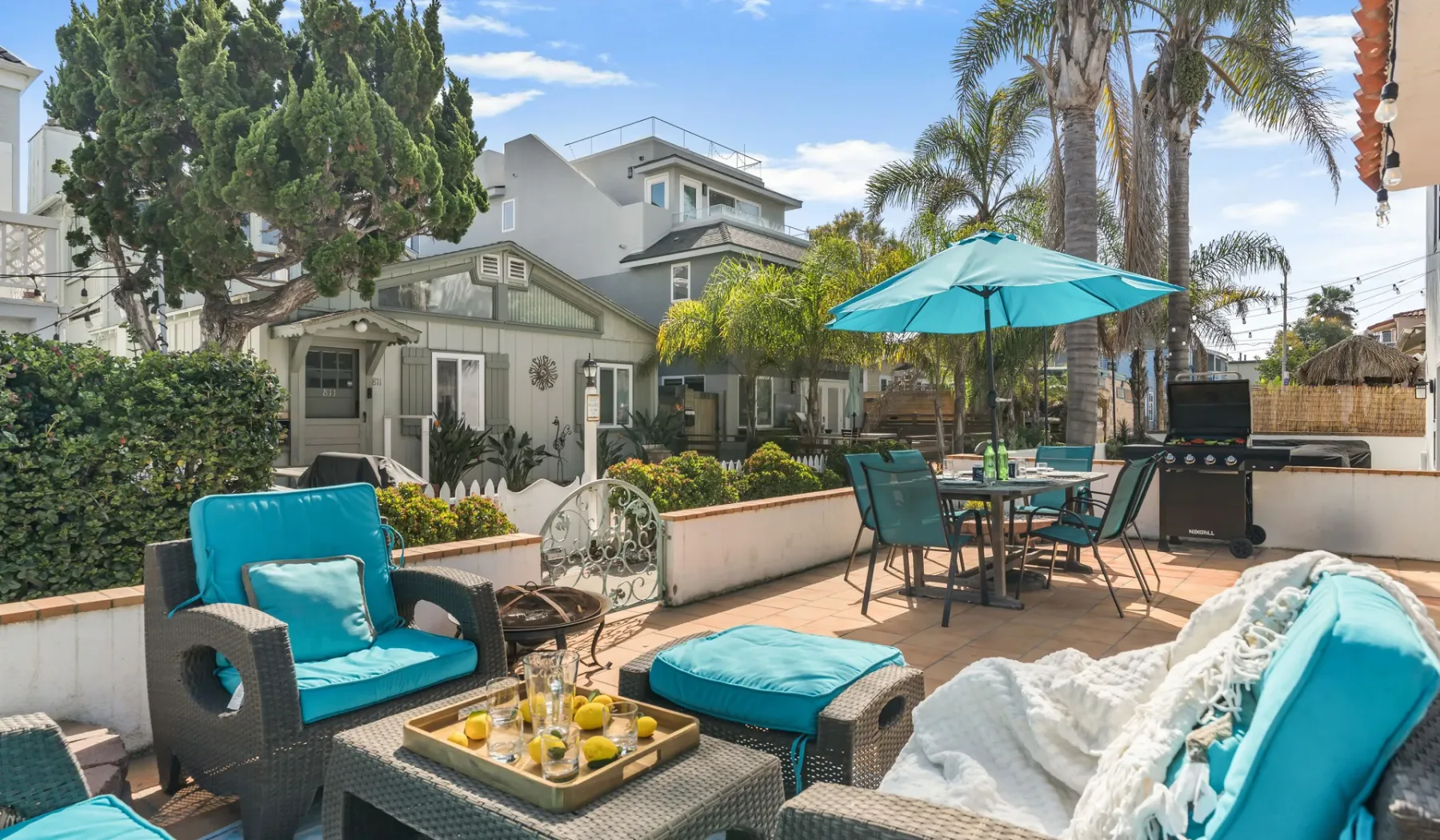 An outdoor patio has turquoise seating, a dining table, and a large umbrella.