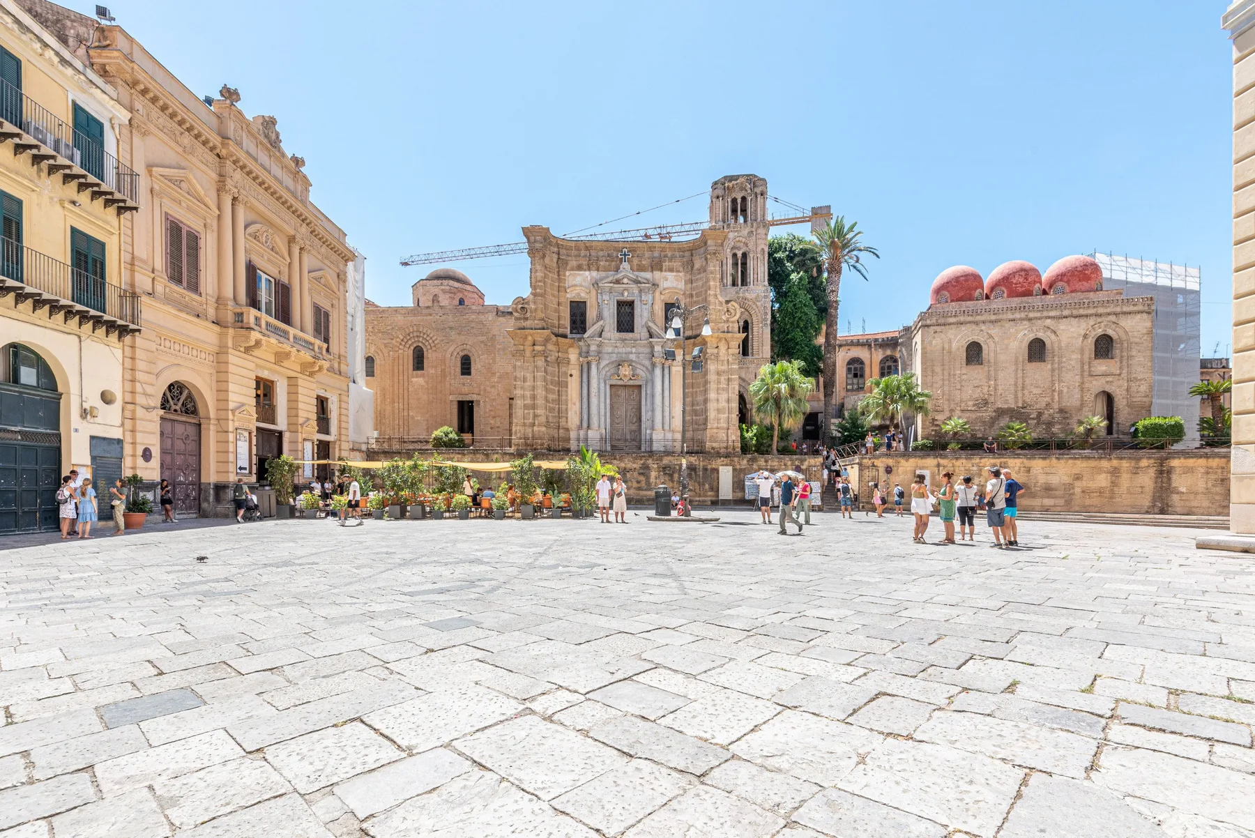 A broad stone-paved plaza opens onto historic buildings beneath a clear sky.