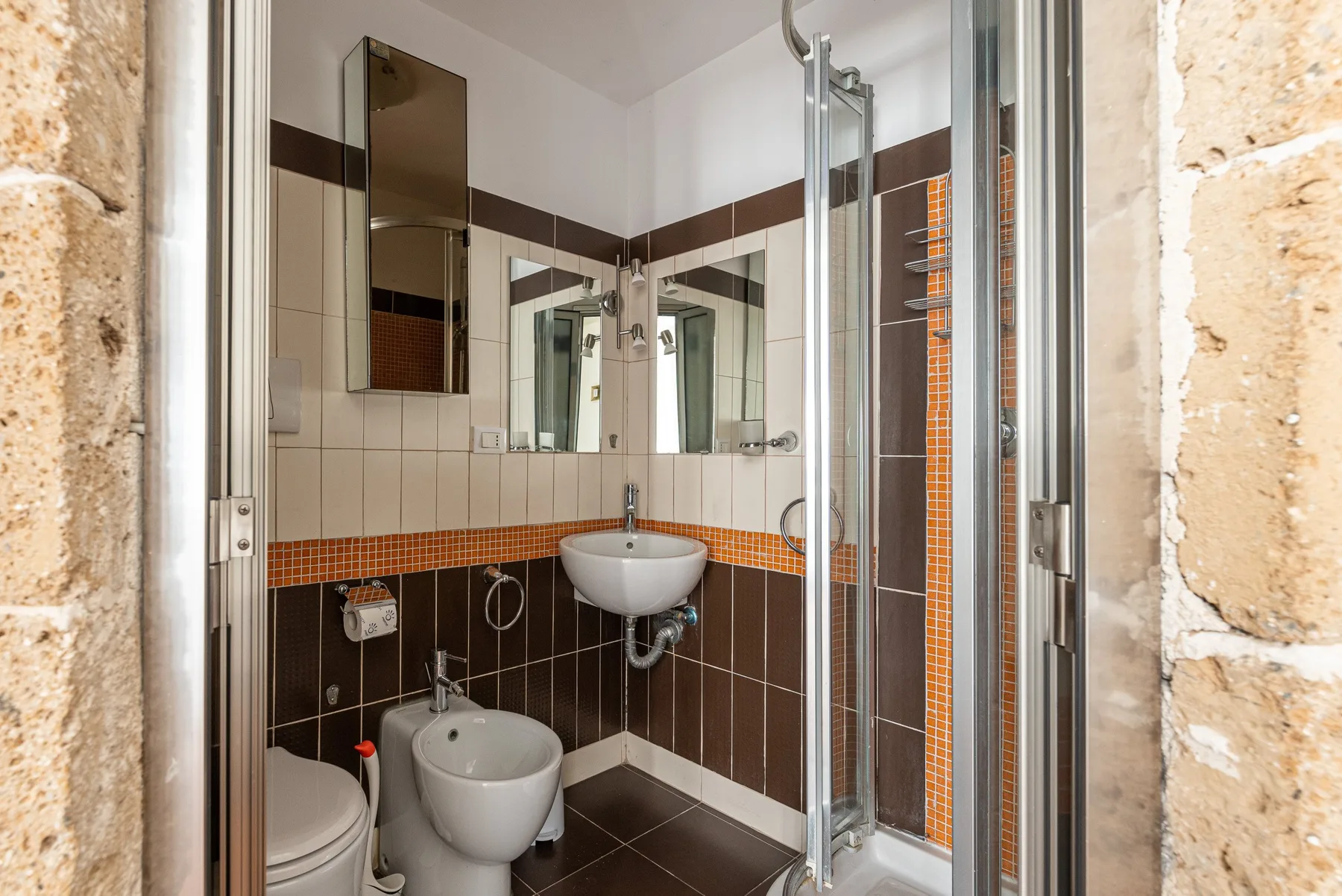 A tiled bathroom with a sink, toilet, bidet, and glass shower.