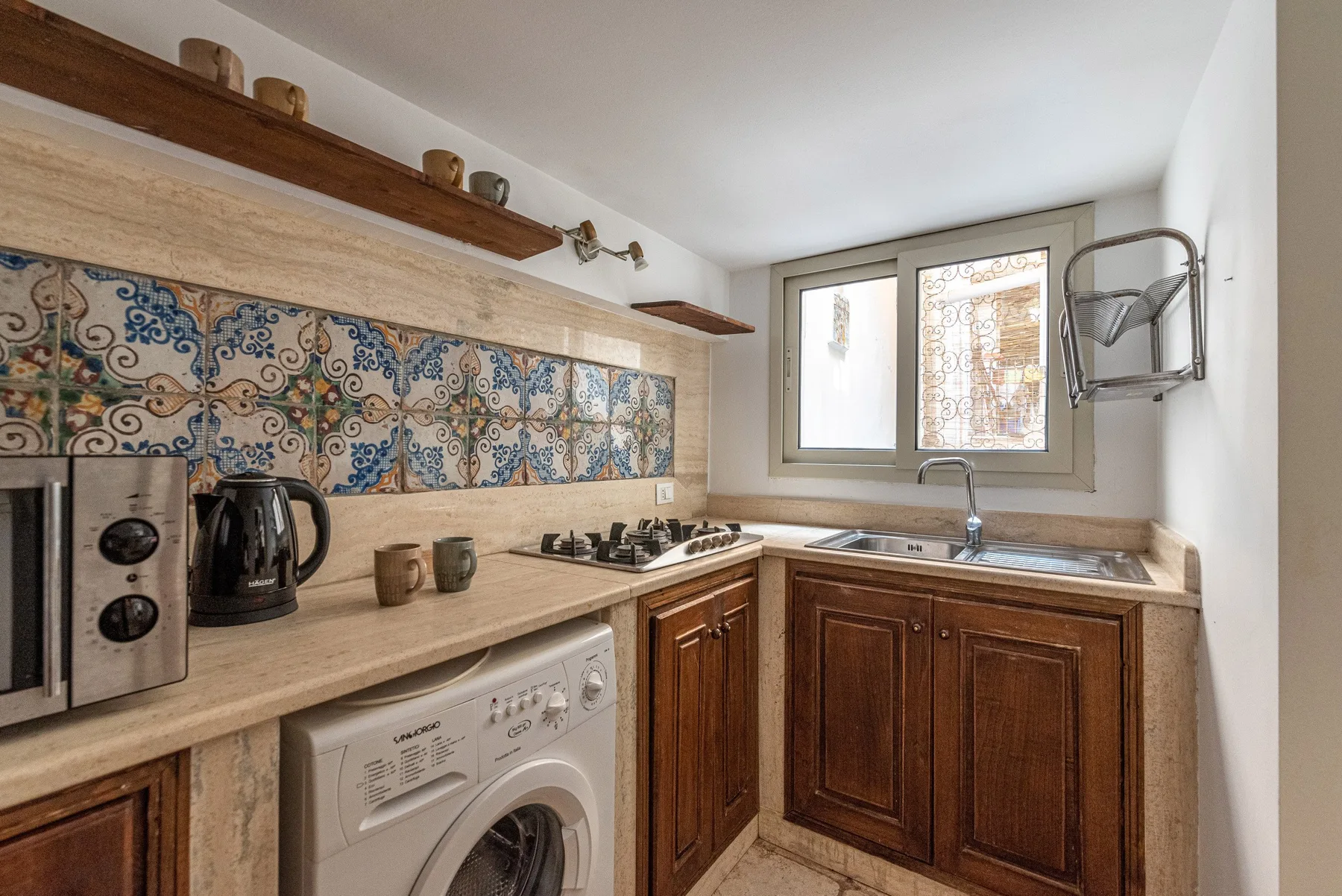 A compact kitchen with wooden cabinets, a tiled backsplash, and a washing machine.