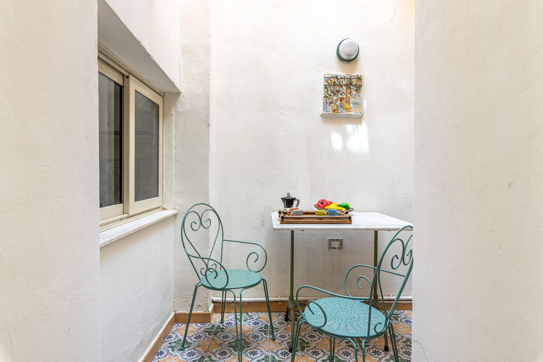 A small patio with a table and metal seating beside a window.