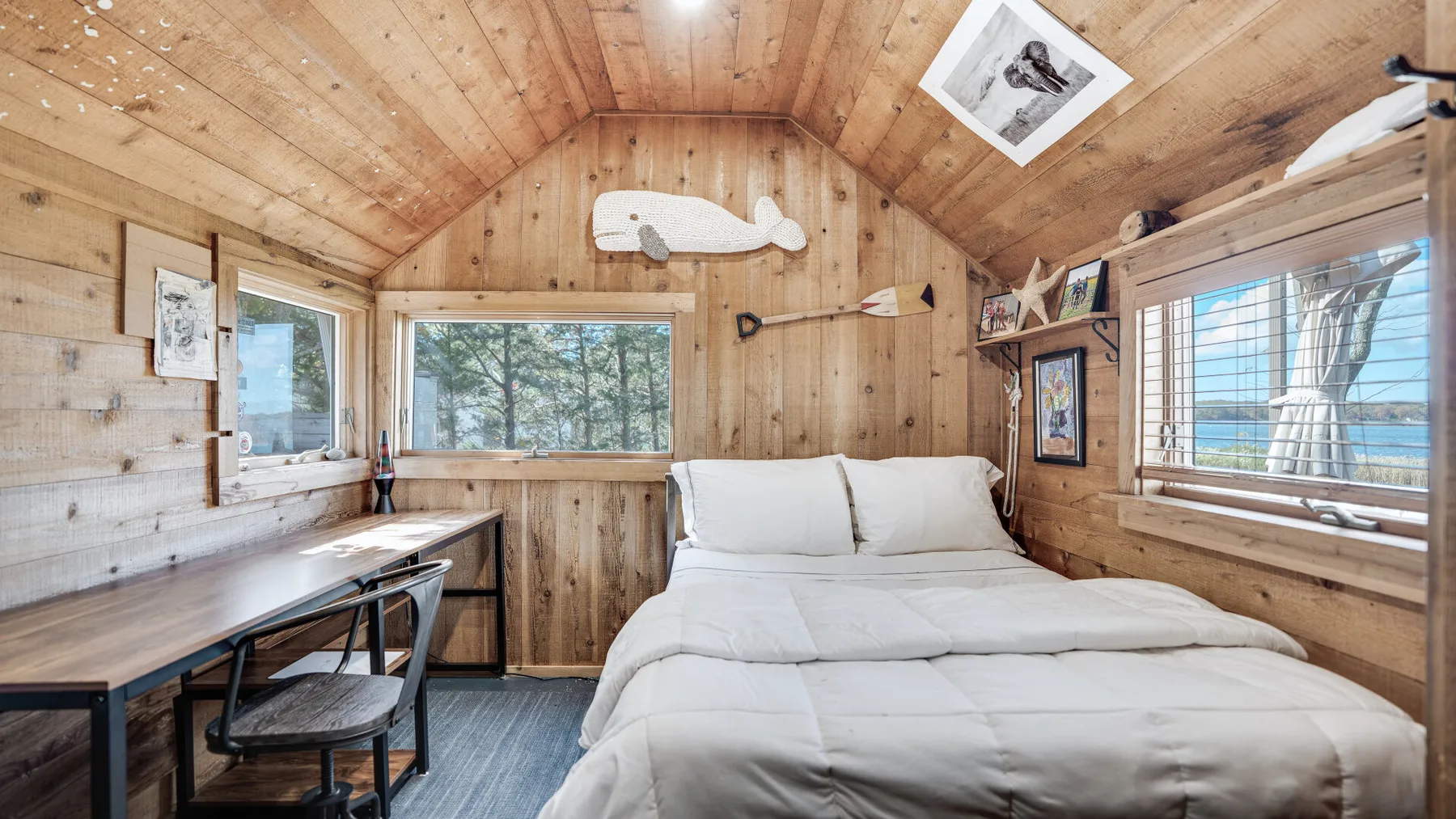 A bedroom with a neatly made bed and wood-paneled walls.