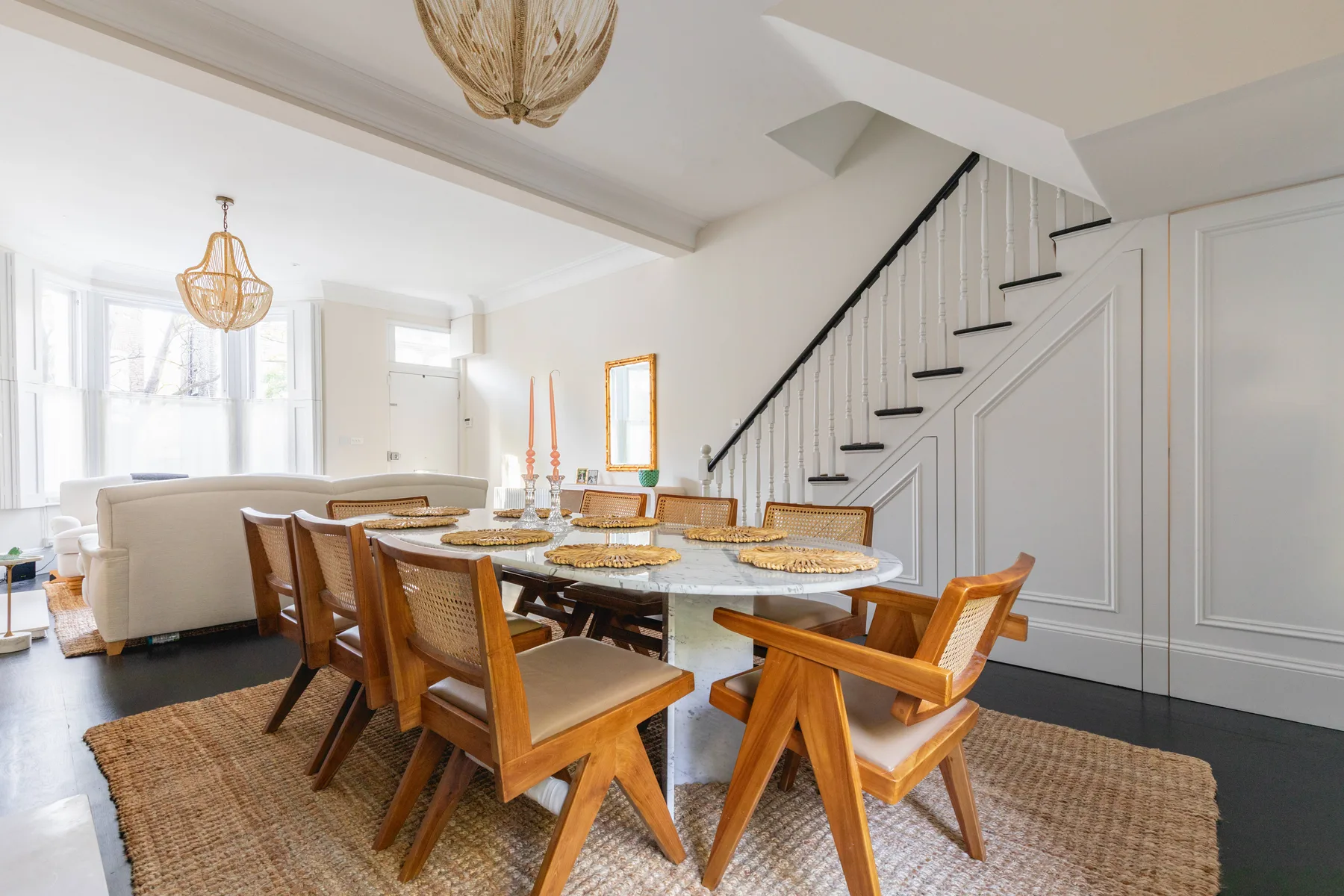 Comedor con una mesa larga y asientos de madera bajo una escalera.