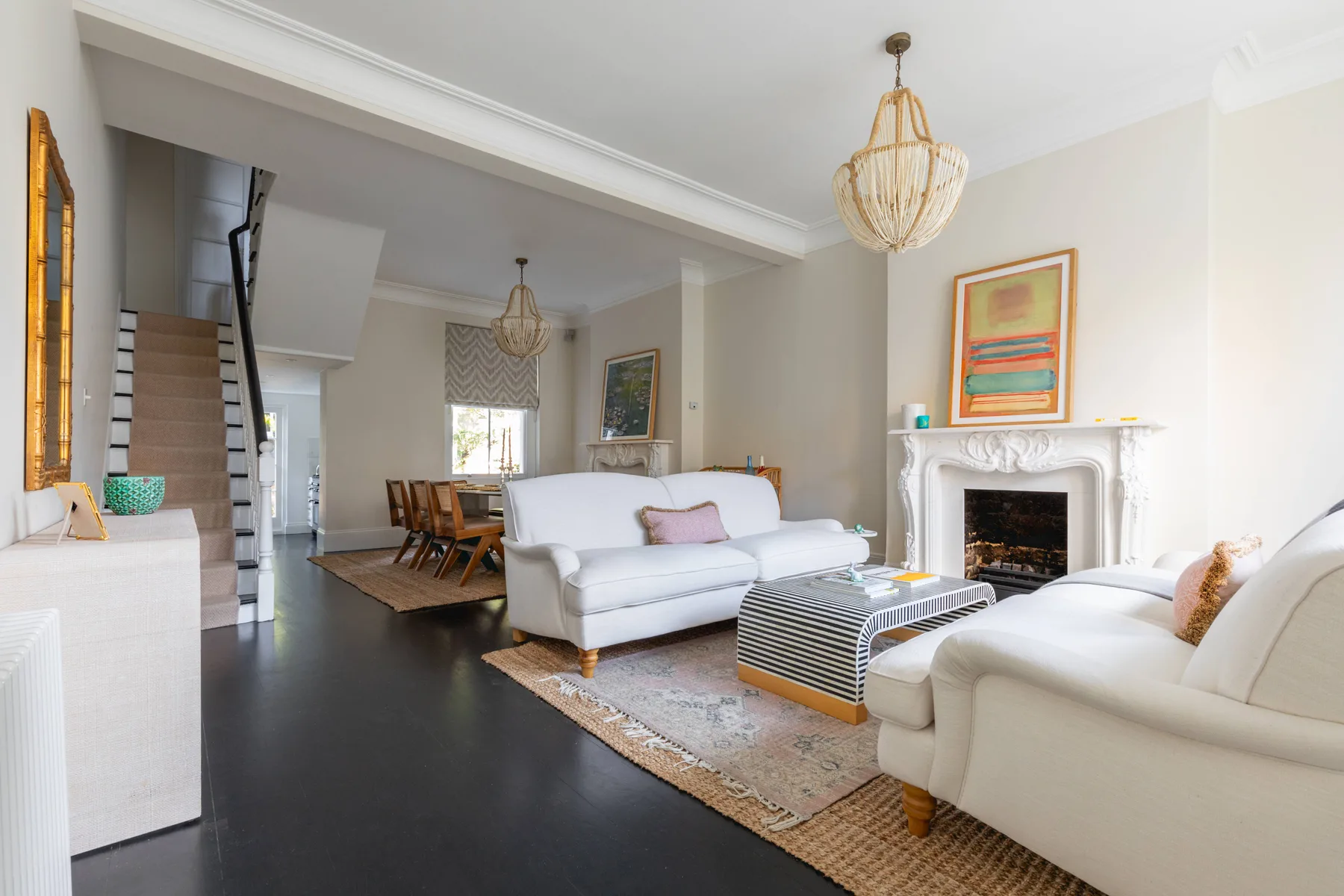 Una sala luminosa con asientos blancos dispuestos alrededor de una chimenea y una mesa de centro.