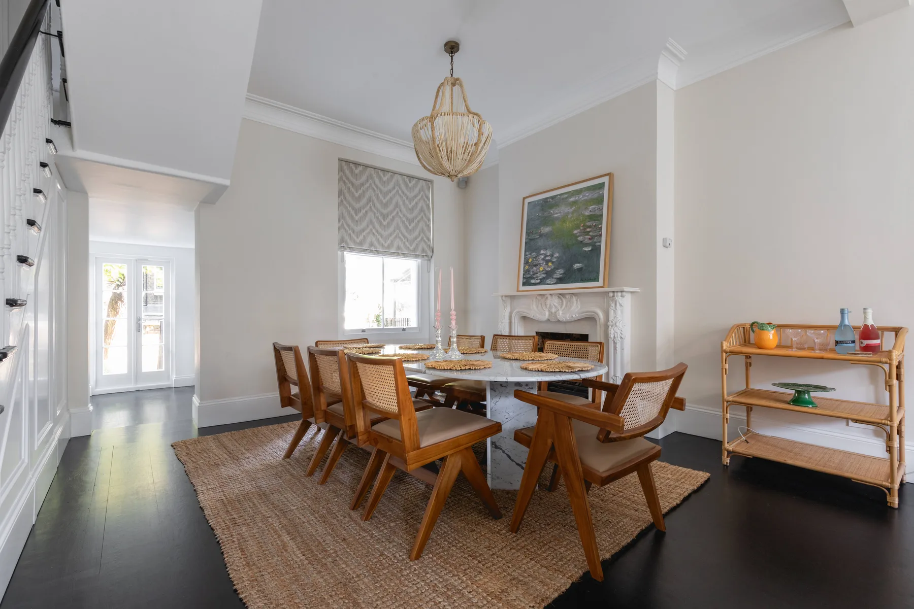 Un comedor con una mesa larga de madera y sillas bajo una lámpara colgante.