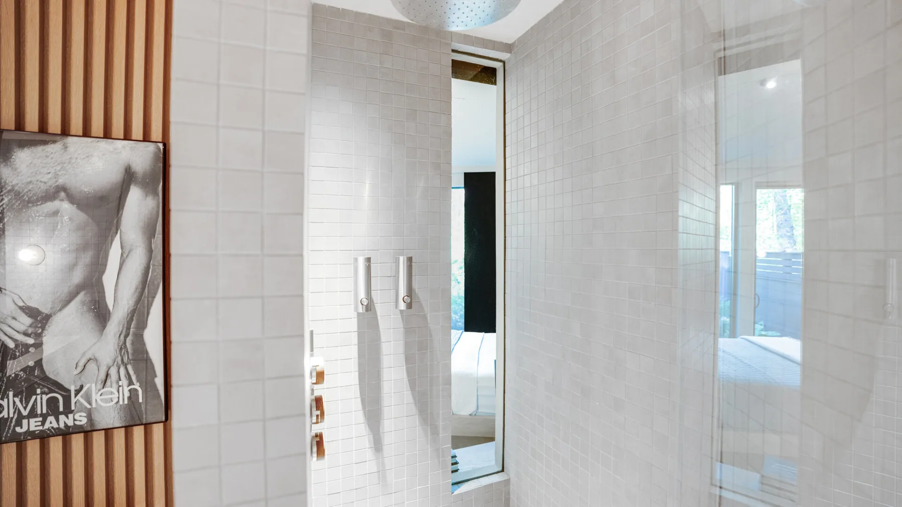 Un baño alicatado con una ducha de vidrio y un póster enmarcado al lado.