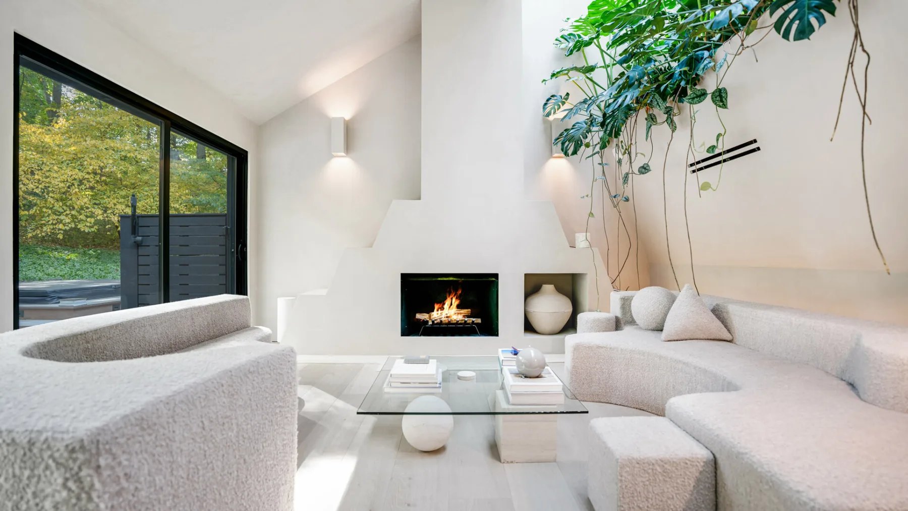 Una sala luminosa con asientos curvos, una mesa de centro de vidrio y una chimenea.